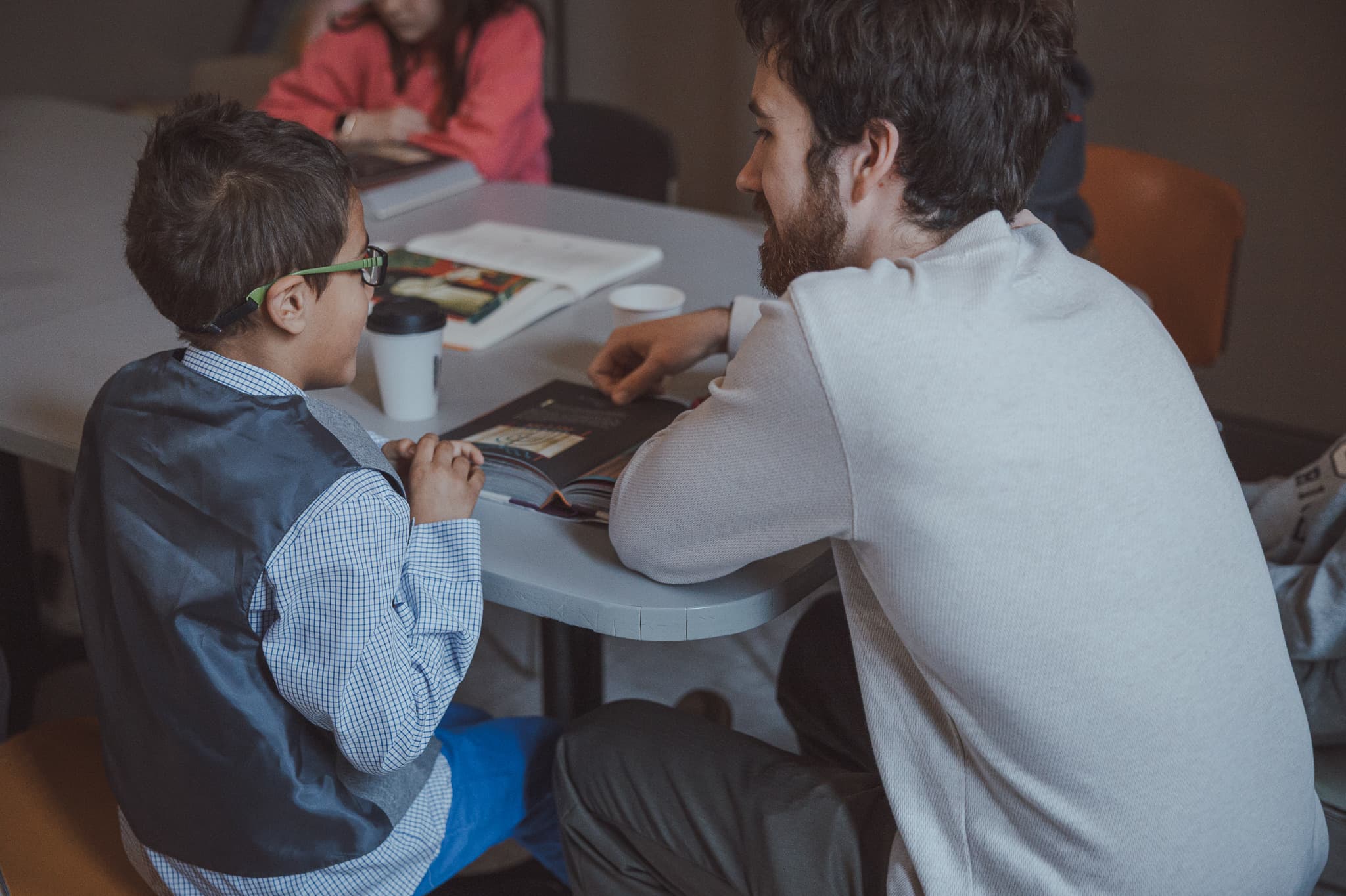 A River City Kids volunteer talking with a child at a table